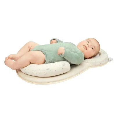 Off-white Babymoov Socosy Floor Pad with a baby in a green onesie resting comfortably on it.