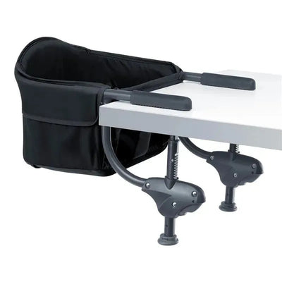 Portable high chair attached to a table, featuring a black fabric seat and sturdy clip-on mechanisms.