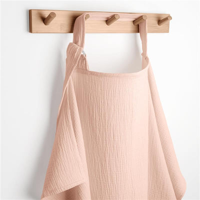 Muslin nursing cover in blush color hanging on a wooden wall hook, featuring a textured fabric design.