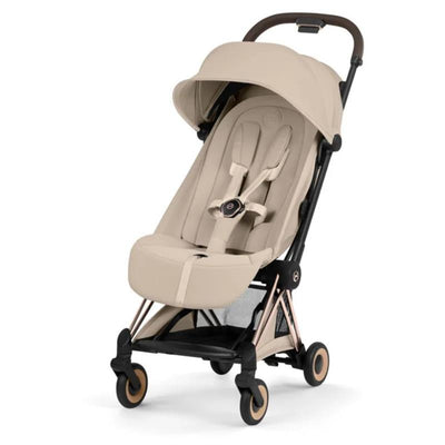 Cybex Platinum Coya Stroller with a rose gold frame and cozy beige seat, featuring a collapsible design and safety harness.