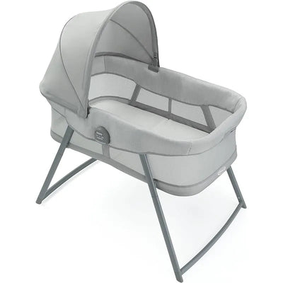Graco Dream More 2-in-1 Travel Bassinet in gray with a canopy and mesh sides, designed for infant sleep and travel.