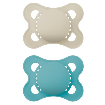Two Mam Original Matte Baby Pacifiers in beige and blue, designed for infants aged 0 to 6 months, showcasing a rounded shape.
