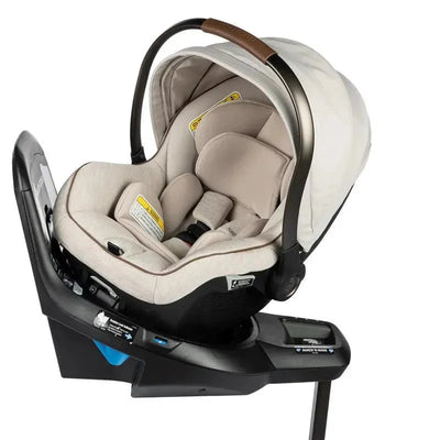 Maxi-Cosi Peri 180 Rotating Infant Car Seat in Desert Wonder, featuring a beige fabric seat, safety harness, and adjustable handle.