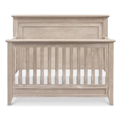 Rustic 4-in-1 convertible crib in sandbar finish, featuring a curved top and slatted front for safety.