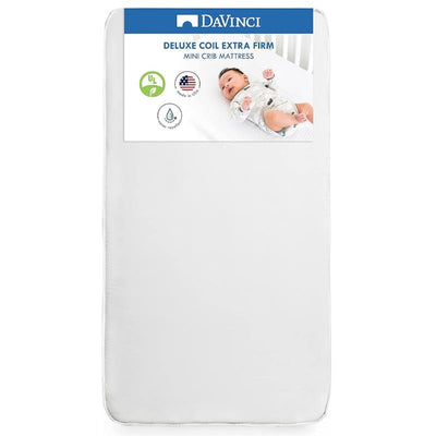 Deluxe Coil Extra Firm Mini Crib Mattress by DaVinci, waterproof, featuring a baby on top and safety certification icons.