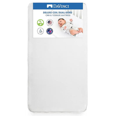 Deluxe Coil Dual-Sided Crib Mattress by DaVinci with a baby lying on it, featuring safety certifications and Made in USA label.