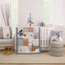 Disney Mickey Mouse nursery crib bedding set featuring a quilt with Mickey, Donald, and Pluto, accompanied by decorative accessories.