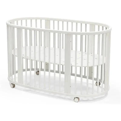 Stokke Sleepi V3 Bed in white, featuring an oval design, slatted sides, and wheels for easy mobility.