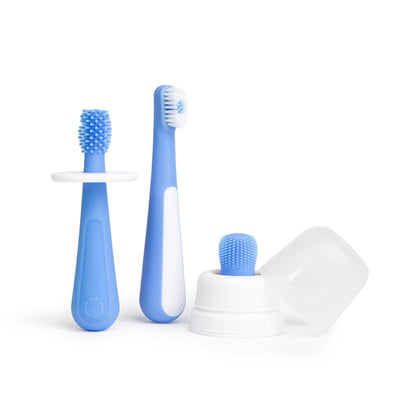 Ubbi Polaris Grow With Me Toothbrush Training Set featuring two blue toothbrushes and a silicone finger brush in a white holder.