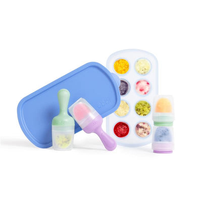 Ubbi Smoothie Purple & Sugar Snap Green Feeder and Freezer Tray Set, with two serving scoops and a tray holding colorful frozen purees.