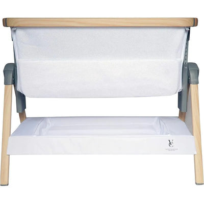California Dreaming Bedside Crib Bassinet by Venice Child, featuring white wood, mesh sides, and a storage compartment underneath.