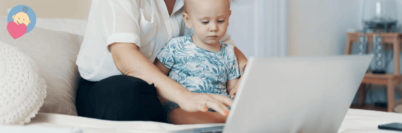 Mom and baby using laptop together on couch, shopping for baby gear online