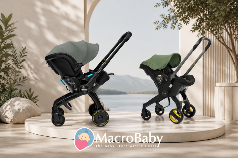 Two modern baby strollers with green canopies and black frames, displayed on a platform near a scenic waterfront.