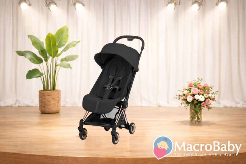 Black lightweight baby stroller with canopy, shown on wooden floor with plants and flowers