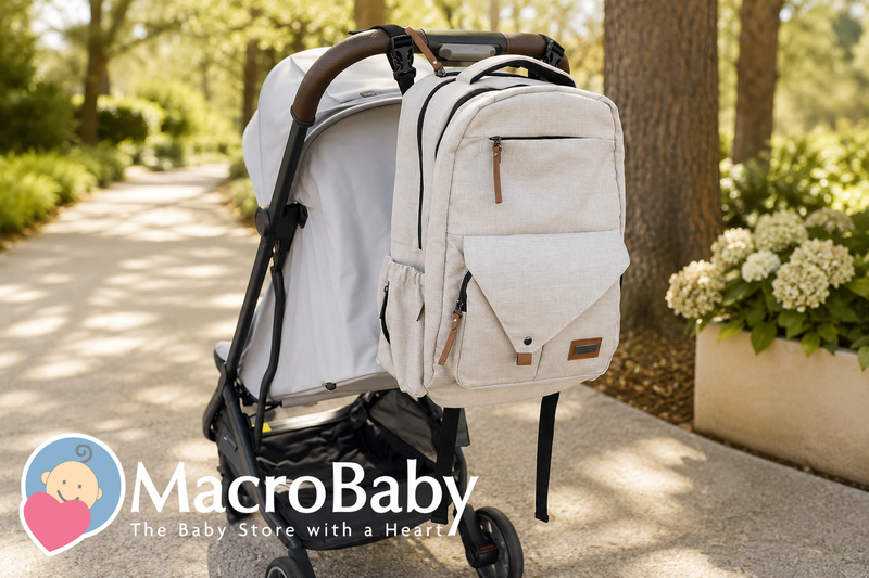 Beige diaper backpack attached to a modern baby stroller in a sunlit park.