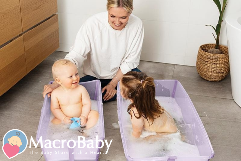 Mom bathing baby and toddler in purple tubs, bubbles, bathroom setting