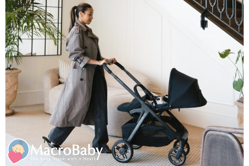 Mom pushing black Kona stroller with baby inside, modern home setting, baby gear essentials