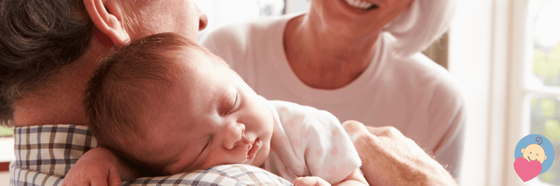 Newborn baby sleeping peacefully in parents' arms, wearing polka dot onesie, near bright window