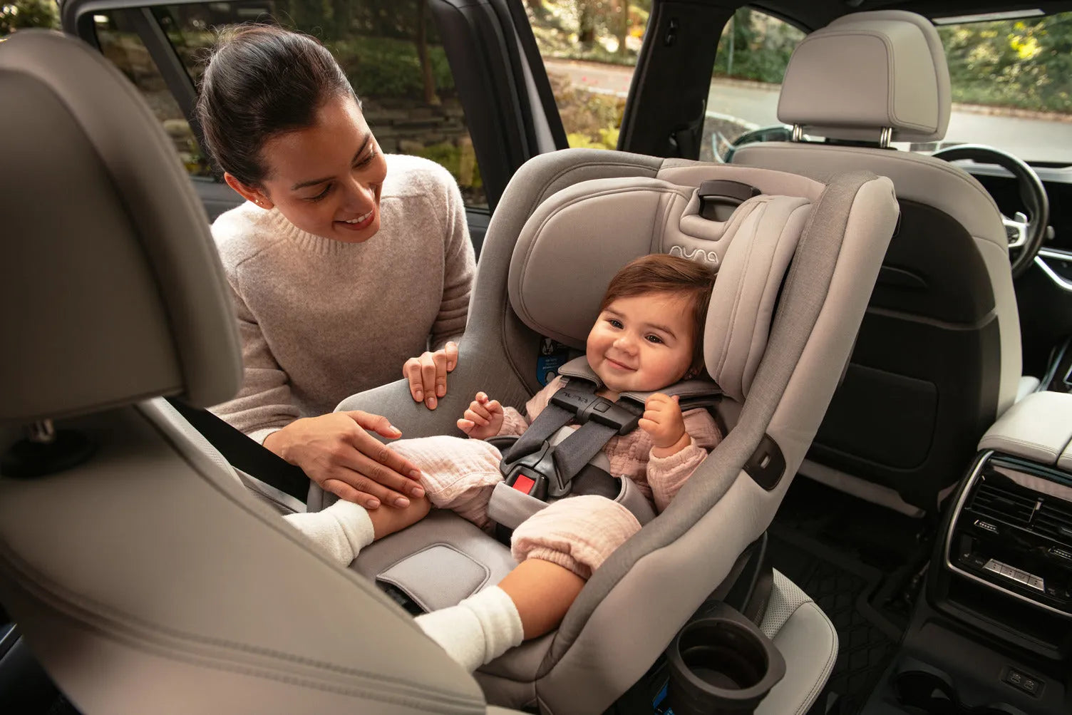 Mom securing baby in Nuna car seat inside vehicle, safe infant travel gear