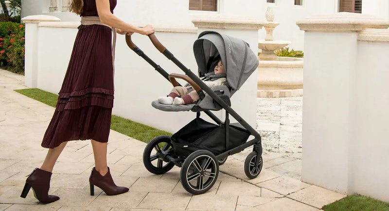 Woman pushing baby in modern stroller on paved walkway, ideal for mom and infant comfort