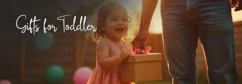 Happy toddler girl holding gift box with adult, outdoor birthday celebration