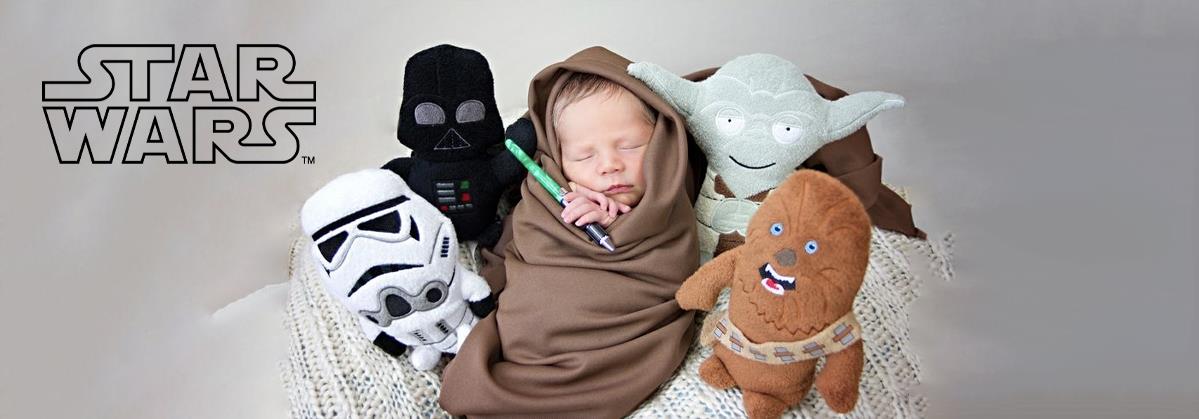 Newborn baby swaddled with Star Wars plush toys: Darth Vader, Yoda, Chewbacca, Stormtrooper