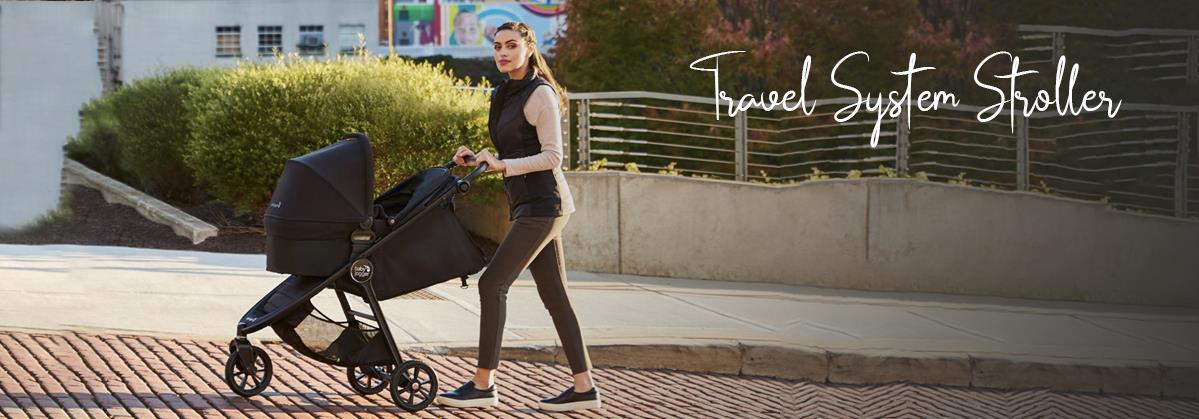 Woman pushing black travel system stroller on brick sidewalk, ideal for urban baby outings