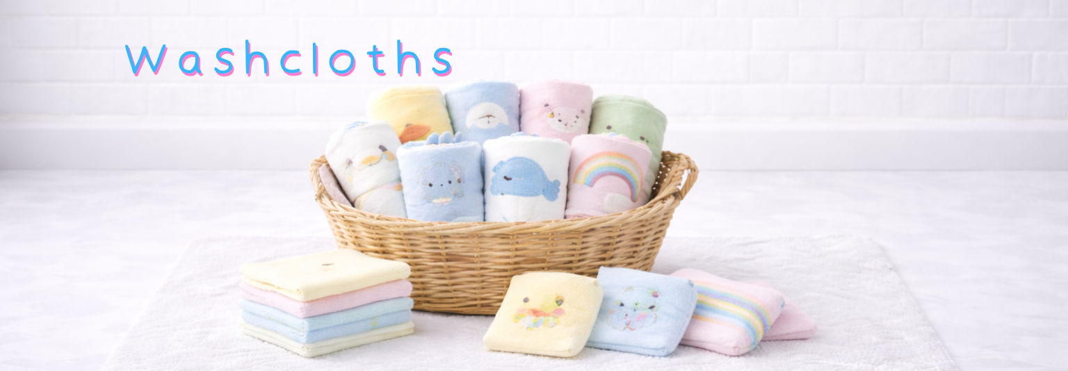 Soft baby washcloths with cute animal and rainbow designs, neatly folded in a wicker basket and on a towel.