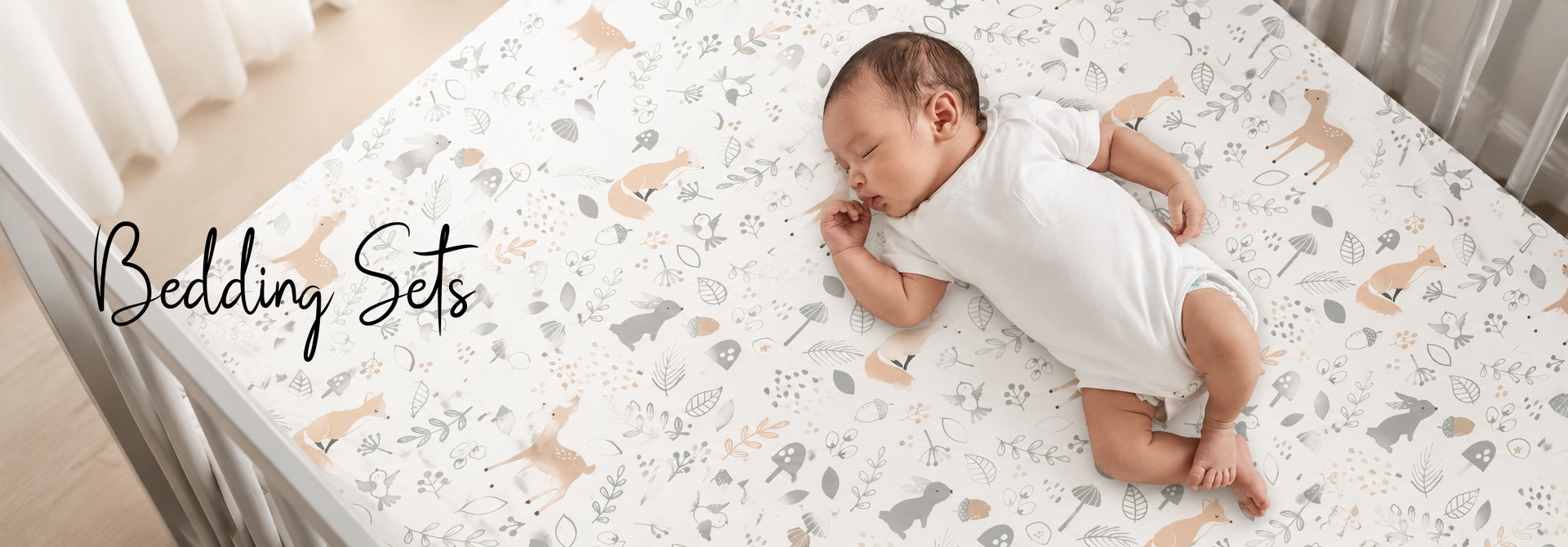 Baby sleeping on woodland-themed crib bedding set with foxes, deer, and leaves pattern