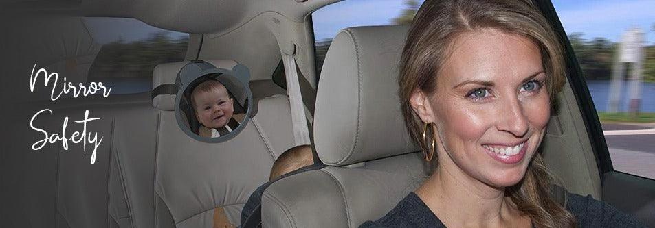 Mom smiles while checking baby in rear-facing car seat mirror for safety during drive