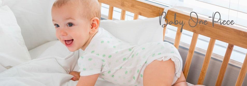 Baby in green polka dot one-piece crawling in wooden crib with white bedding