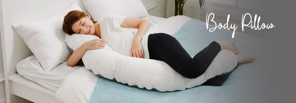 Pregnant woman sleeping comfortably with a white body pillow on a bed, ideal for maternity support.