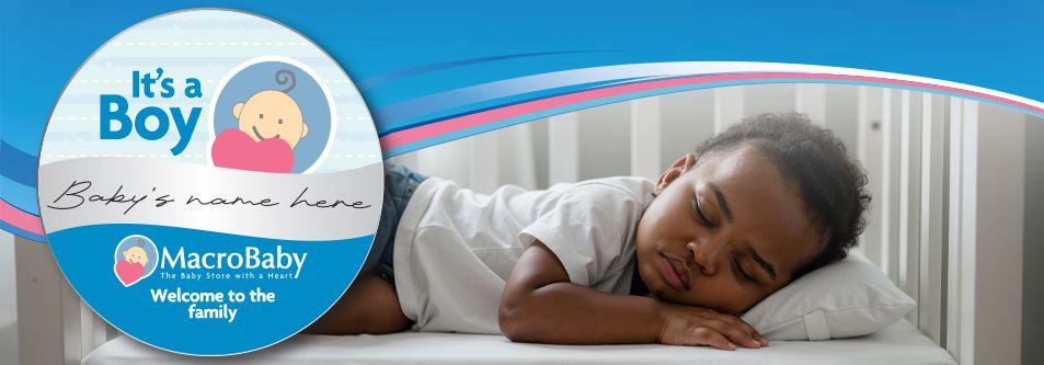 Sleeping baby boy in crib with 'It's a Boy' announcement graphic, baby bedding, and MacroBaby welcome tag