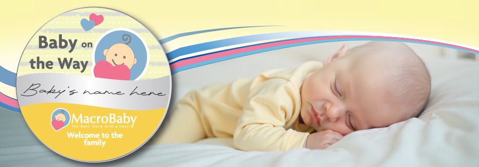 Sleeping baby in yellow onesie with 'Baby on the Way' announcement card