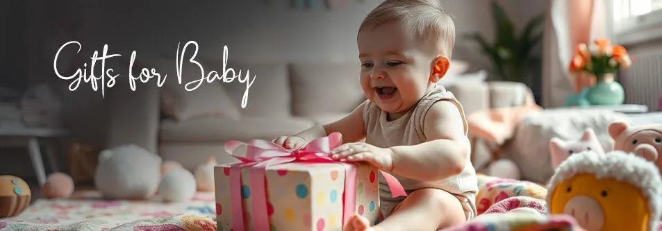 Happy baby opening colorful gift box with pink bow, surrounded by toys and soft bedding