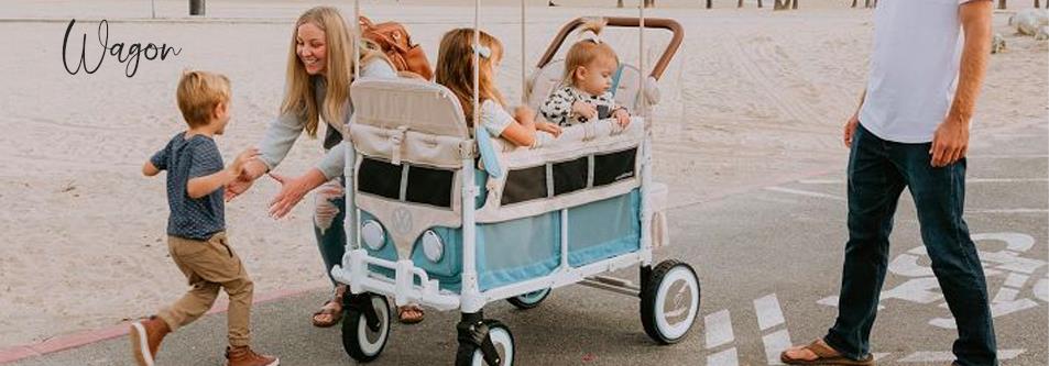 Family enjoying beach day with retro-style wagon stroller carrying kids, perfect for baby gear and outdoor adventures.