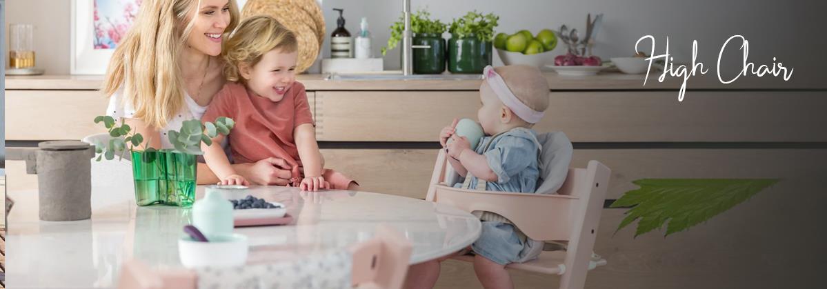 Baby in wooden high chair at kitchen table with mom and toddler, modern nursery decor
