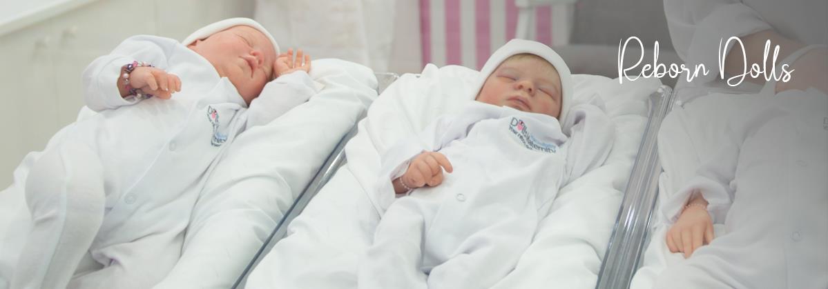 Realistic reborn baby dolls in white hospital gowns sleeping in nursery cribs