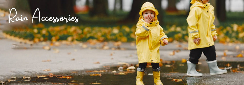 Toddler in yellow raincoat and boots playing in autumn puddles, rain accessories for kids