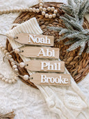 Wooden name tags for baby gifts: Noah, Abi, Phil, Brooke on cozy blanket with beads and pine