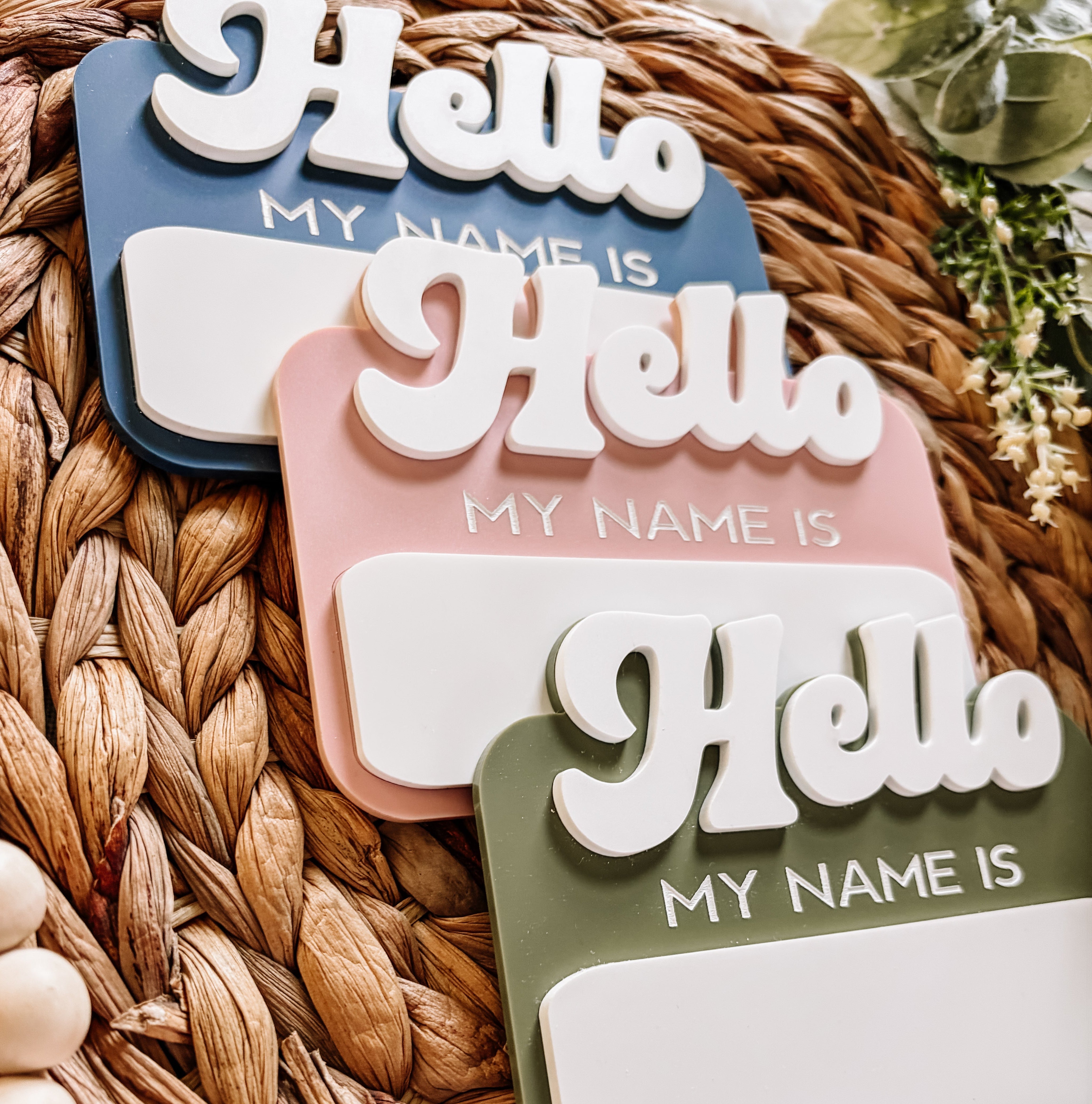 Hello My Name Is name tags in blue, pink, green on woven mat
