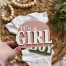 It's a Girl sign with baby onesie and wicker basket background