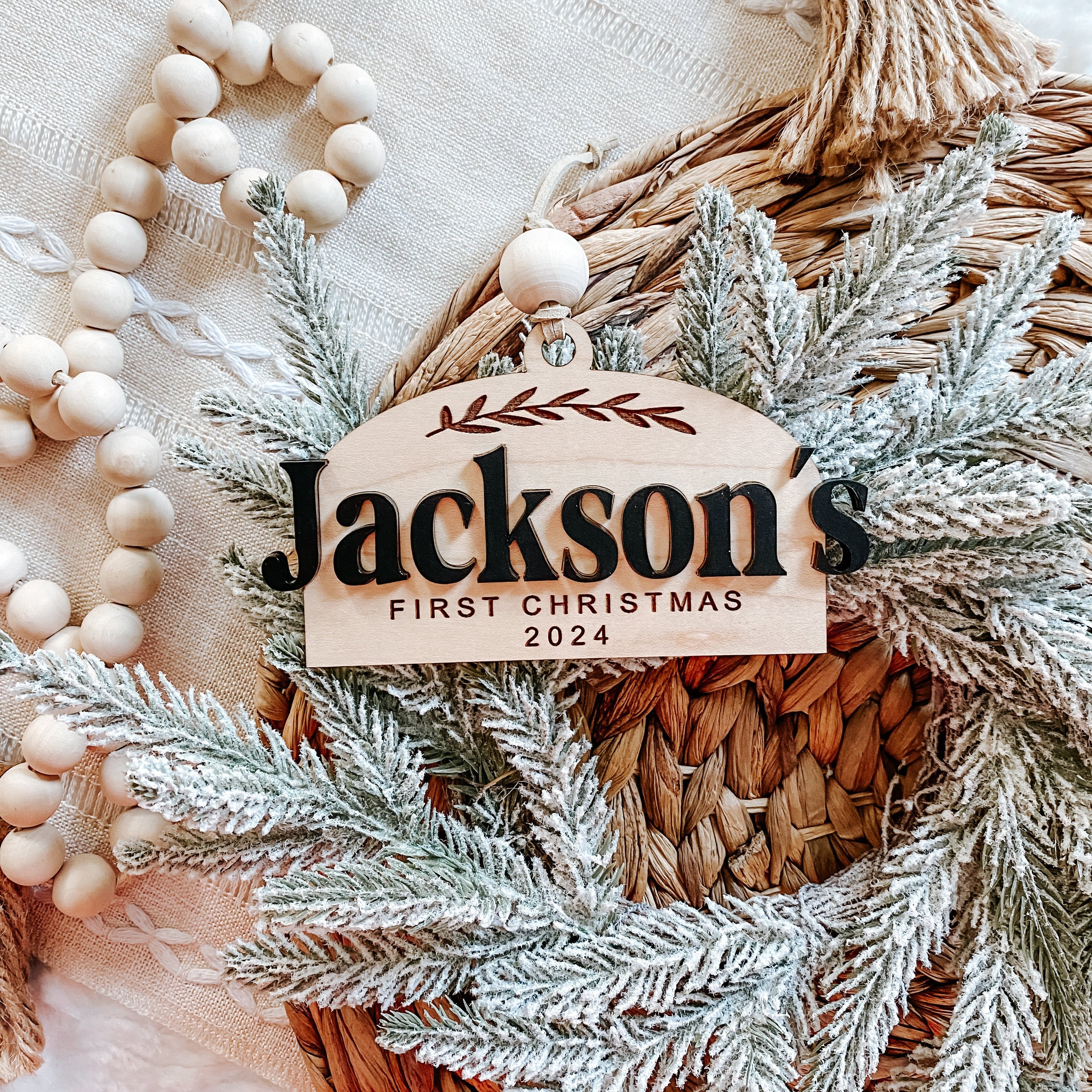 Jackson's First Christmas 2024 wooden ornament with frosted greenery and beads