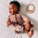Baby in brown patterned onesie with 7 months milestone sign