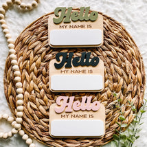 Hello My Name Is wooden signs in green, black, pink on woven mat with beads and greenery
