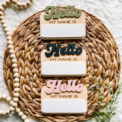 Hello My Name Is wooden signs in green, black, pink on woven mat with beads and greenery
