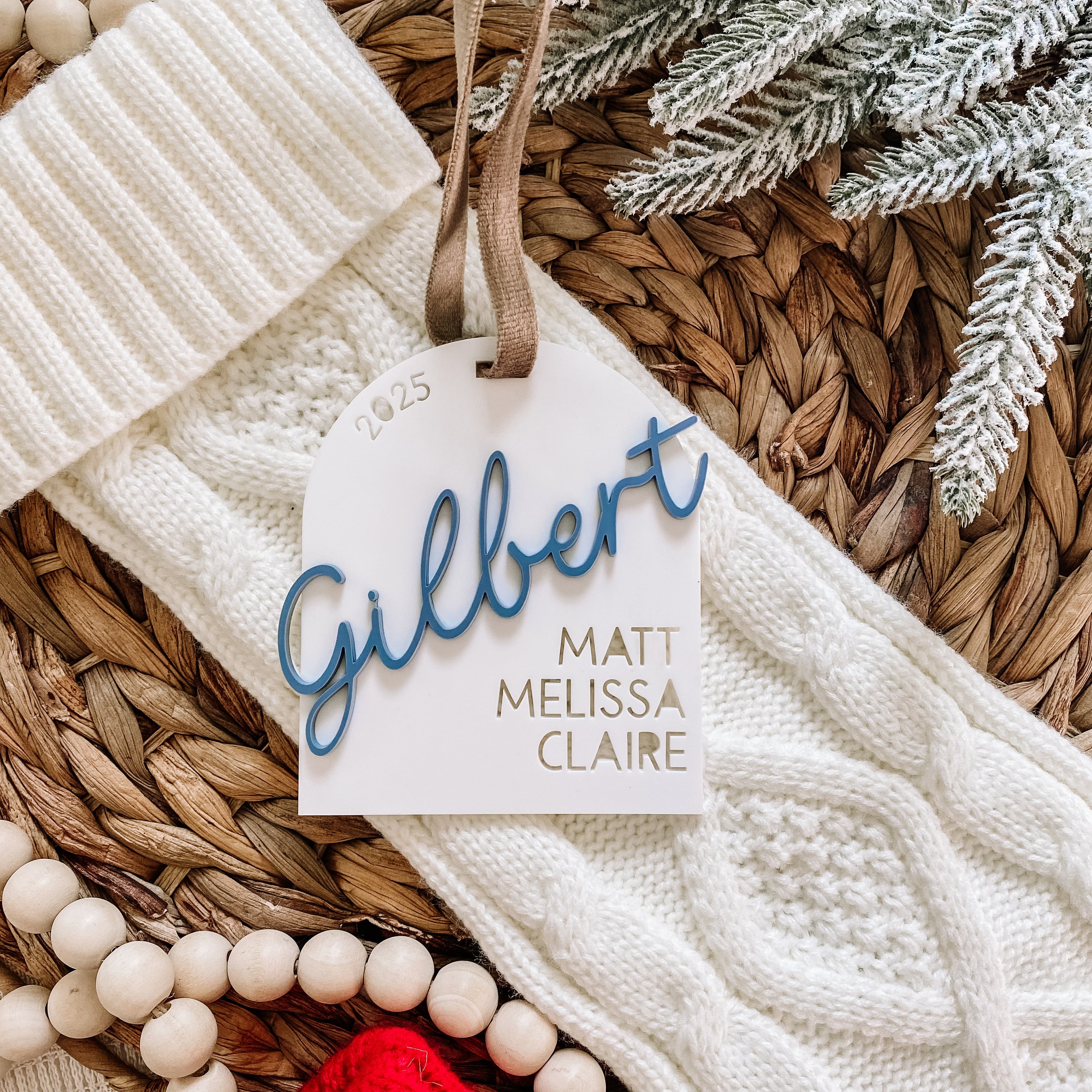 Personalized 2025 Gilbert family ornament with names Matt, Melissa, Claire, on cozy knit blanket with festive wreath.
