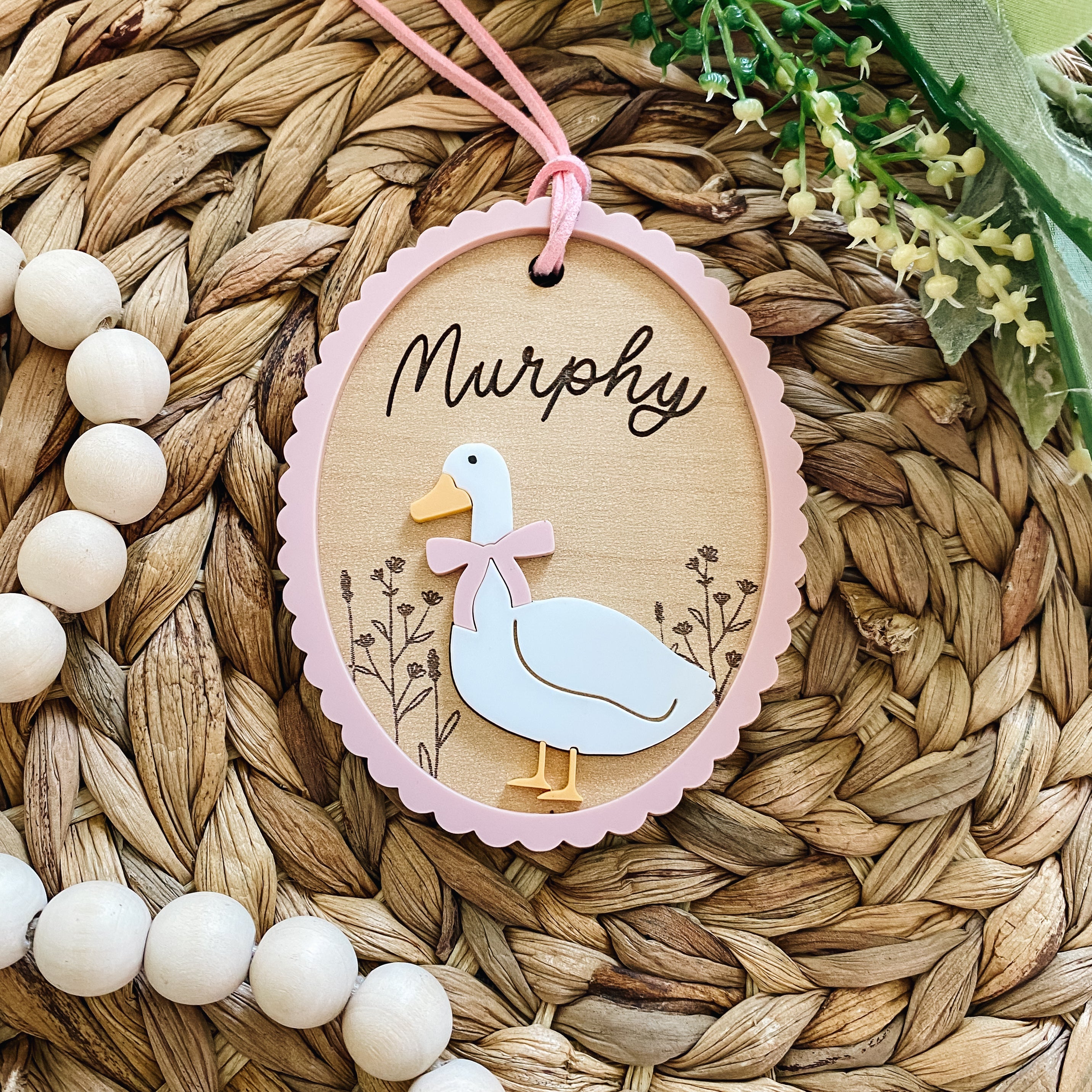 Personalized baby name tag with duck design, pink scalloped border, and 'Murphy' script, ideal for nursery decor or baby gifts.