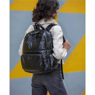 Diaper bag backpack in black polar, displayed on a person facing away, featuring a sleek design and padded straps.