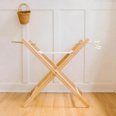 Design Dua Stationary Bassinet Stand in natural pine wood against a white wall.